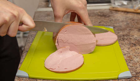 The cook cuts the sausage with a knife. close-upの写真素材