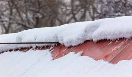 Snow on the red roof of the house. Winterの写真素材