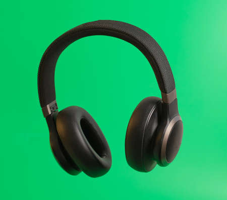 Black audio headphones isolated on green background. close-up