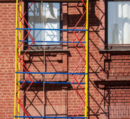 Metal scaffolding at the brick wall of the building.の写真素材