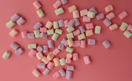 Multicolored candies on a pink background.