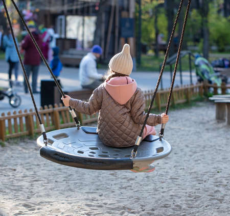 Girl rides on a swing in the park.の写真素材