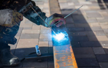 A worker works with metal welding at a construction site. Technology