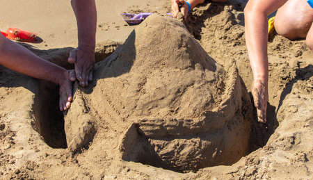 People are building a sand tower on the seashore.