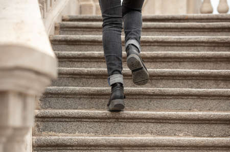 A girl in black jeans walks up the stairs.