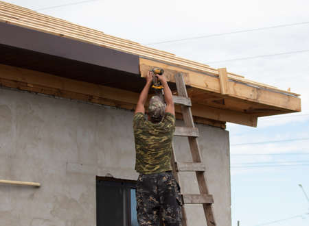 Workers install metal roofing on the wooden roof of a house. Technology