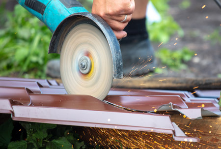 A worker cuts a metal roof for the roof of a house.