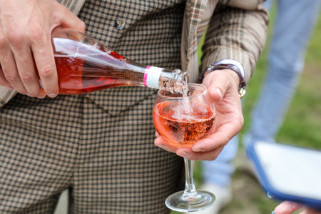 The groom pours a glass of champagne to the wedding guests. close-up