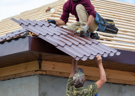 Workers install metal roofing on the wooden roof of a house. Technologyの写真素材