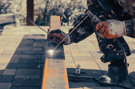 A worker works with metal welding at a construction site. Technology