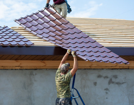 Workers install metal roofing on the wooden roof of a house. Technologyの写真素材