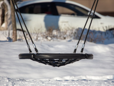 Children's swing in the snow in the park. Winter