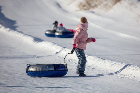 A child rolls down a snow tubing from a mountain. Winterの写真素材