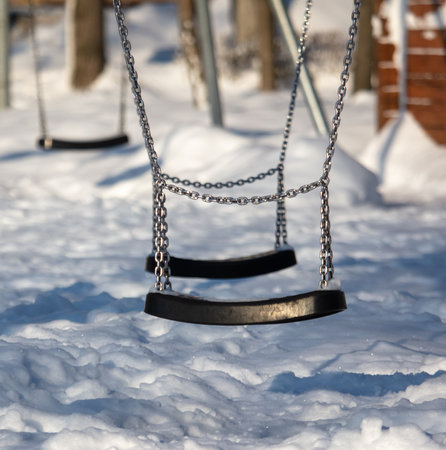 Children's swing in the snow in the park. Winter