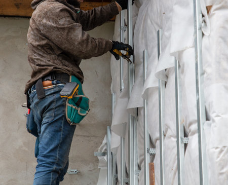 The worker insulates the walls of the house from the outside. Preparation for the installation of saiing.の写真素材
