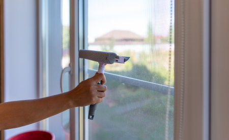 The girl washes the glass on the window in the room.の写真素材