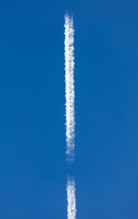 White lines from an airplane against a blue sky.の写真素材