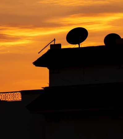 Black silhouette of the roof of the house with an antenna on the background of the sunset.の写真素材