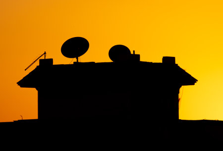House roof silhouette with satellite dishes at sunset. backgroundの写真素材