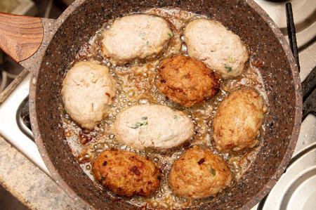 Minced meat cutlets are fried in a frying pan in oil.