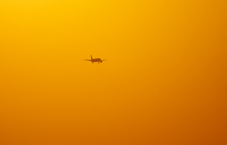Silhouette of an airplane coming in for landing at sunset. backgroundの写真素材
