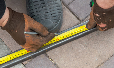 A worker measures metal at a construction site. Technologies