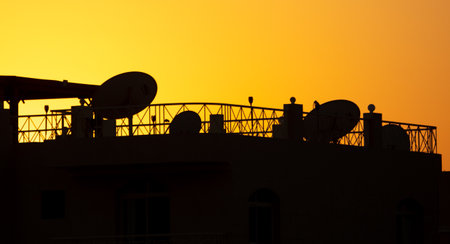 House roof silhouette with satellite dishes at sunset. backgroundの写真素材