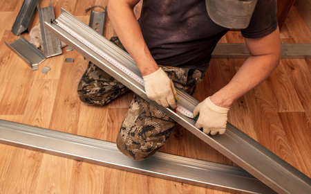 A man installs a metal profile for a wall in a roomの写真素材
