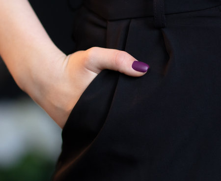 The girl's hand is in the pocket of black pants. close-up
