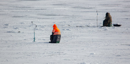 Fishermen on ice catch fish in winterの写真素材