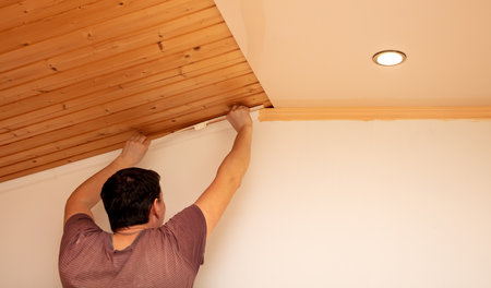 A worker paints moldings on the ceiling with a brush. home renovationの写真素材