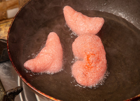 Red chips are fried in oil in a frying pan.の写真素材