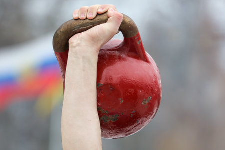 Raised red weight in a man's hand. Sport