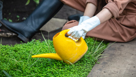 Girl watering plants from a watering can in the park. Natureの写真素材