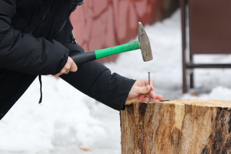 A boy hammers a nail into a log.の写真素材