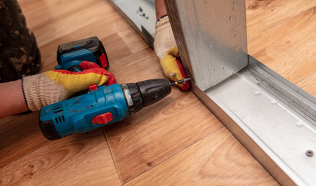A man installs a metal profile for a wall in a roomの写真素材