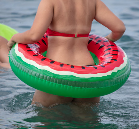 A girl in a swimsuit with an inflatable circle bathes in the sea.の写真素材