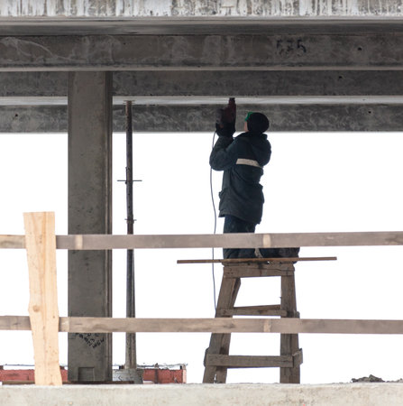 A man drills the ceiling of a house under construction.