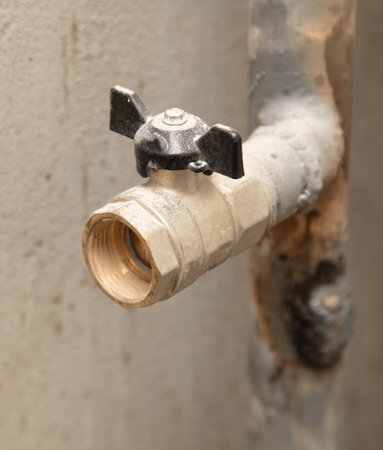 Metal faucet with a pipe on the wall in the repair room.