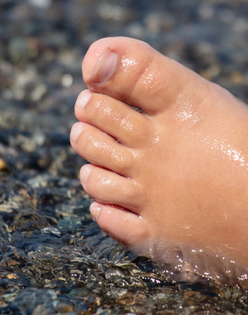 Man's foot on a pebble beach.の写真素材
