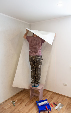 A worker pastes wallpaper on the walls in a room.の写真素材