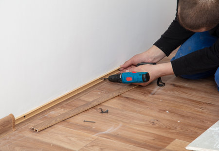 A worker installs a skirting board on the floor in a room.の写真素材