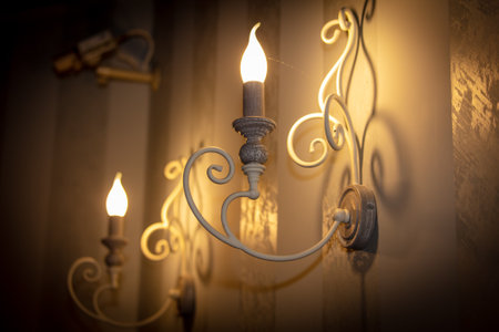 Vintage candlestick with burning candle on a wall background.の写真素材