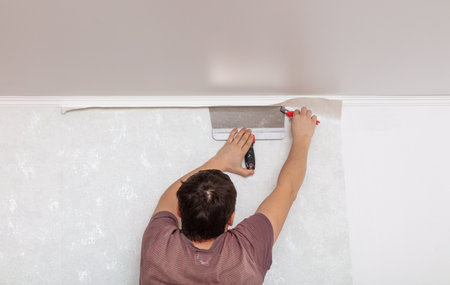 A worker pastes wallpaper on the walls in a room.の写真素材