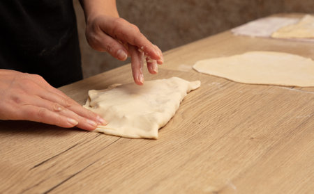 Female hands kneading dough on a wooden table. close-up.