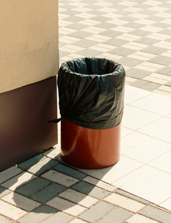Trash can in front of a wall in a city park.の写真素材