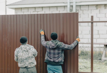Workers install a metal profile fence.の写真素材