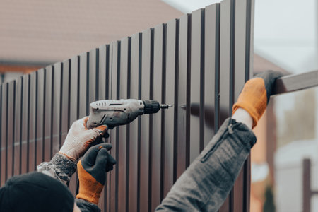 Workers install a metal profile fence.の写真素材