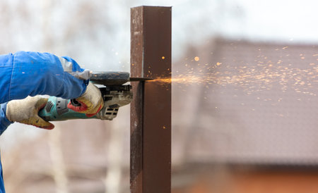 A worker is cutting metal to install a fence.