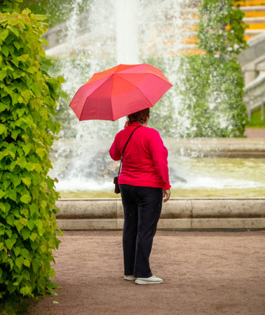 Woman with red umbrella in the park.の写真素材